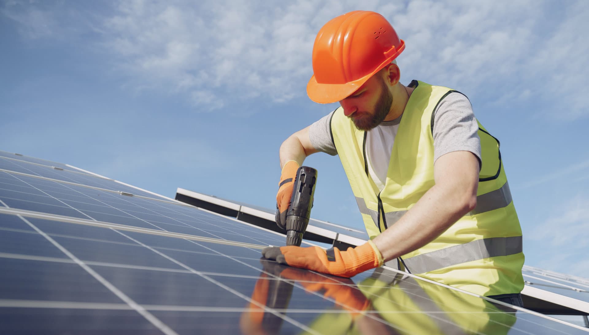 Técnico instalando paneles solares con taladro y equipo de seguridad